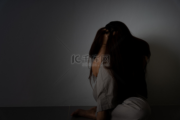 悲伤的女人抱着她的膝盖，独自坐