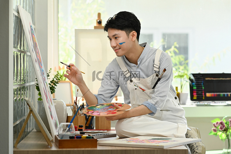 快乐的亚洲男性艺术家在艺术工作