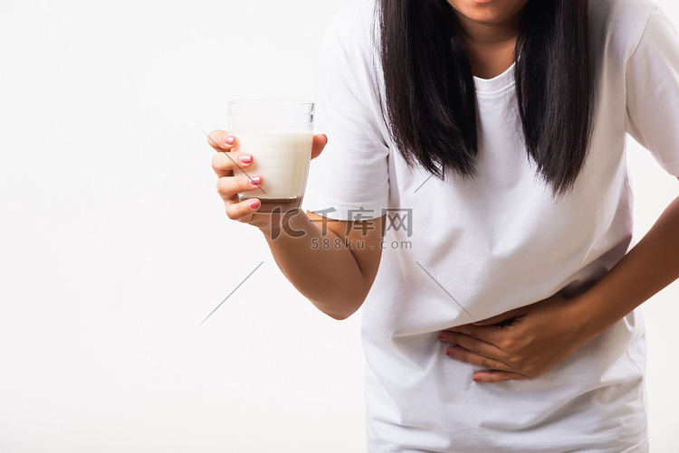 女人用手拿着玻璃牛奶，她胃痛得