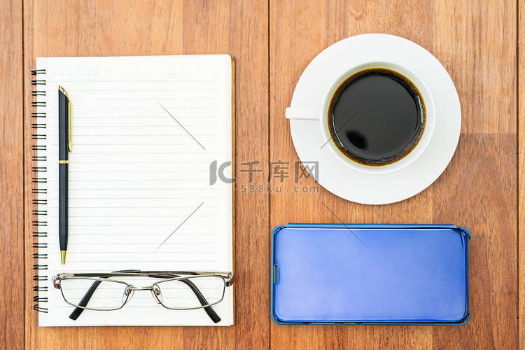 木桌上咖啡杯和手机的顶视图图像