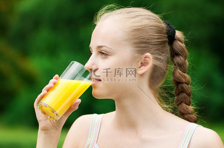 喝橙汁的年轻女子。