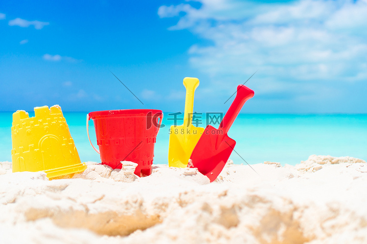 白色沙滩上的儿童沙滩玩具和草帽