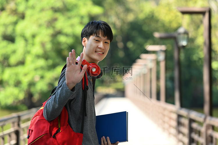 微笑的亚洲男大学生背着背包和书