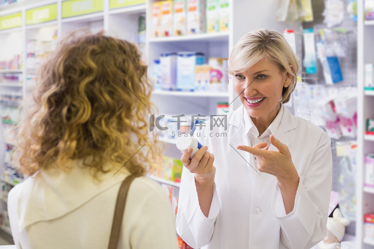 药剂师拿着一瓶药与顾客交谈