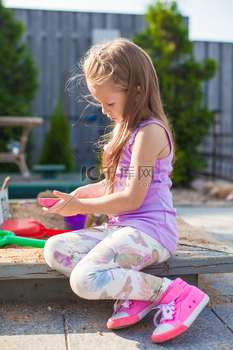 可爱的小女孩在院子里玩沙箱玩具