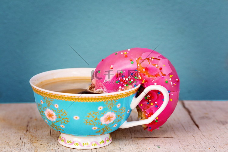 泡在咖啡里的粉色釉面甜甜圈