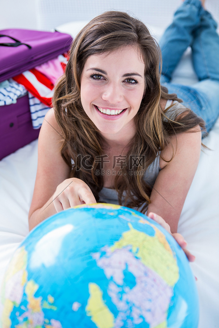 拿着手提箱的美丽的妇女指向地球