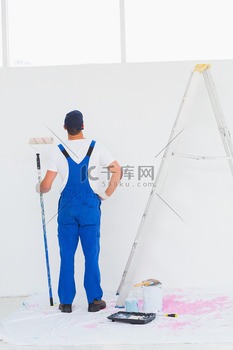 家里有油漆滚筒检查墙的杂工