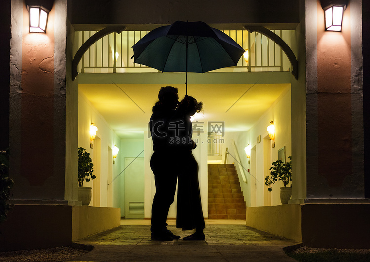情侣在伞下接吻的剪影