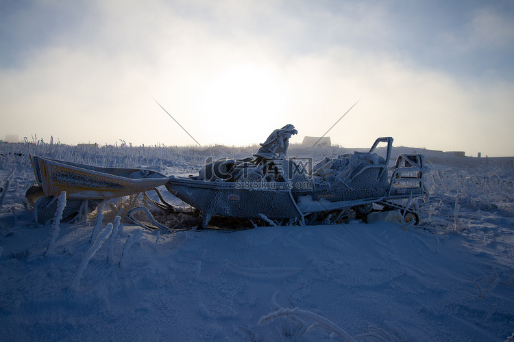 坐在白雪覆盖的风景上的旧雪地车