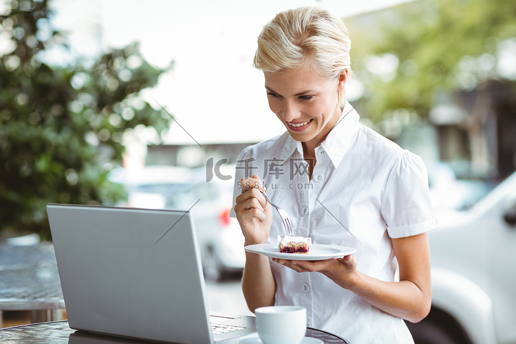 年轻女人用笔记本电脑吃一块馅饼