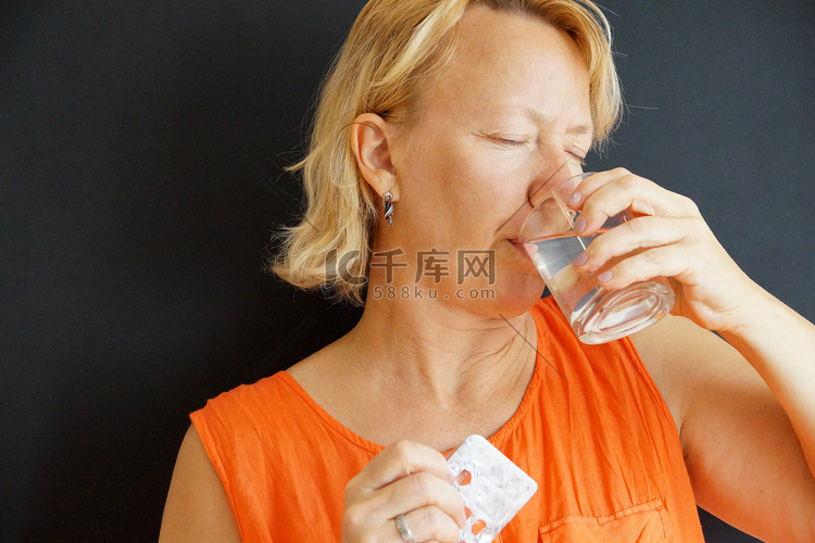 生病的女人用水喝药丸，黑色背景