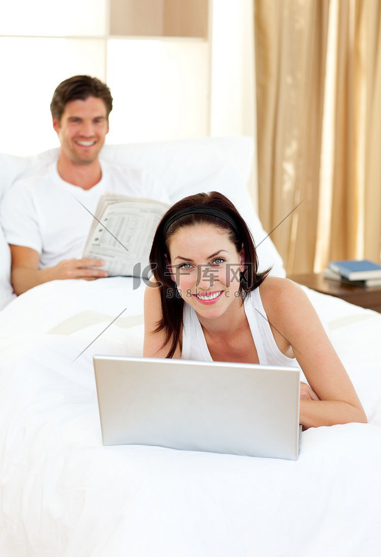 女人用她的笔记本电脑和男人看报