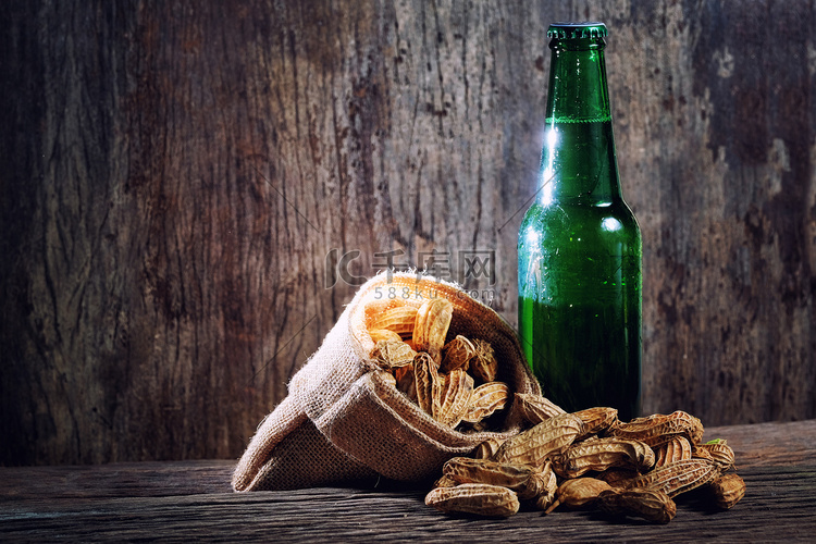 木背景中绿瓶中的花生和啤酒