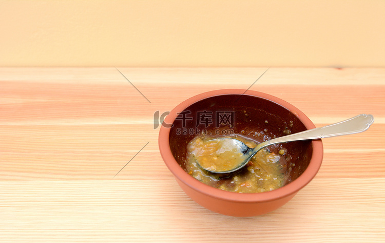 木桌上放着勺子的空碗汤