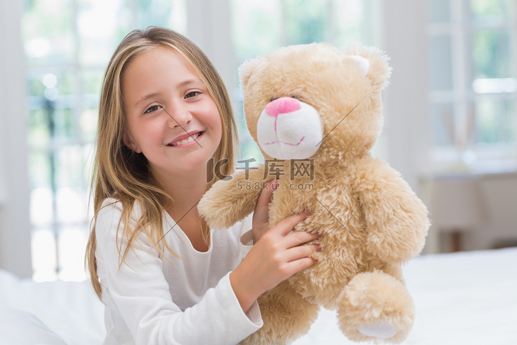 拿着她的玩具熊的愉快的小女孩