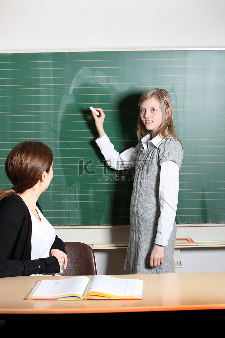 学生在教室里，在黑板上写字。
