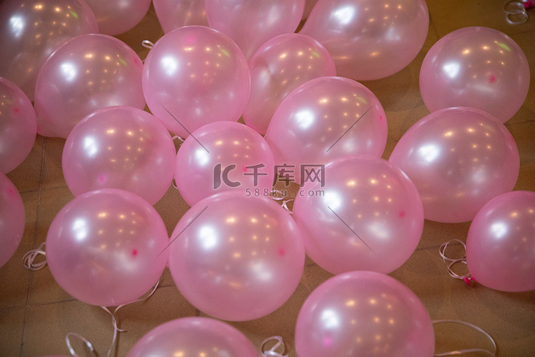 粉红色的充气气球躺在瓷砖地板上