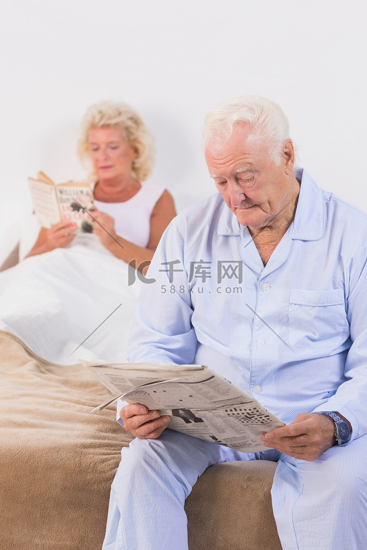 年迈的夫妇在床上看书