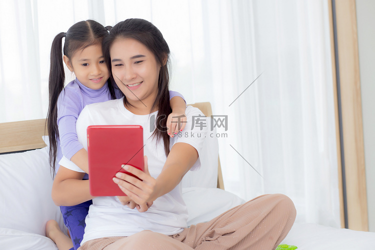 年轻的亚洲妈妈和女儿在平板电脑