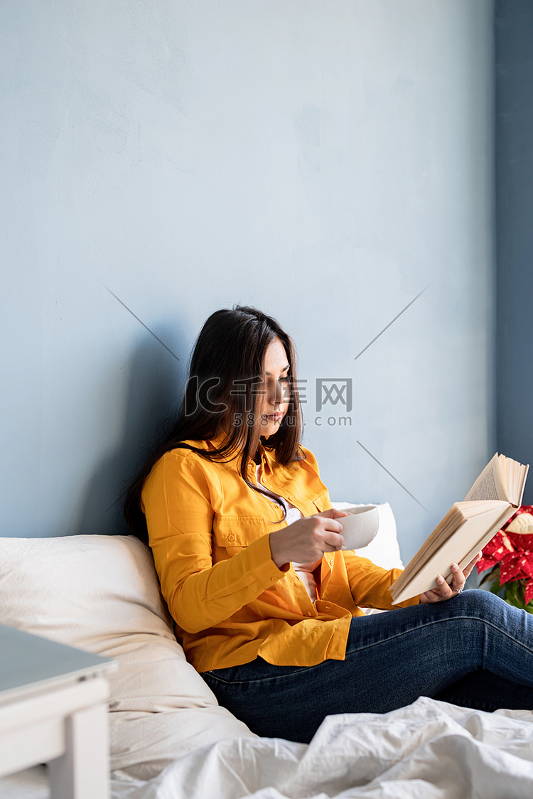 年轻的黑发女人坐在床上吃羊角面