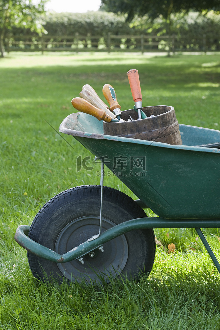 草地上带园艺工具的裁剪独轮车的