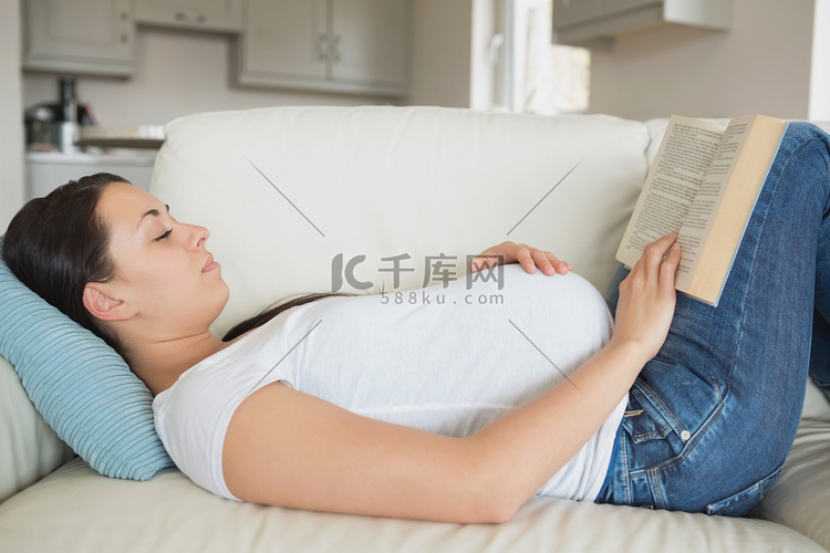 在沙发上看书的年轻孕妇