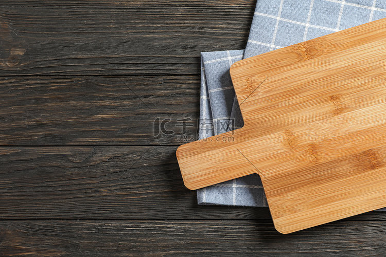 木制背景上带厨房毛巾的切板，文