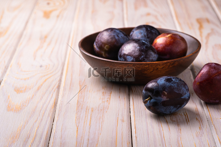 棕色木碗中鲜甜的李子果实