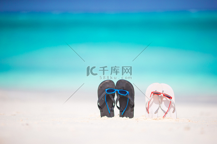 夏季拖鞋与白色沙滩上的太阳镜。