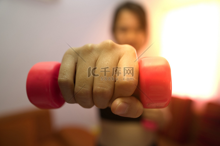 亚洲女性训练举起粉红色哑铃来锻