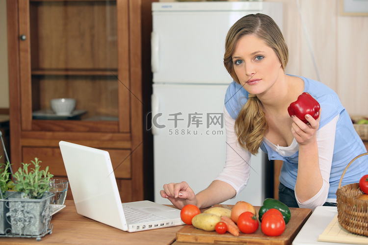 在笔记本电脑旁边做饭的女人