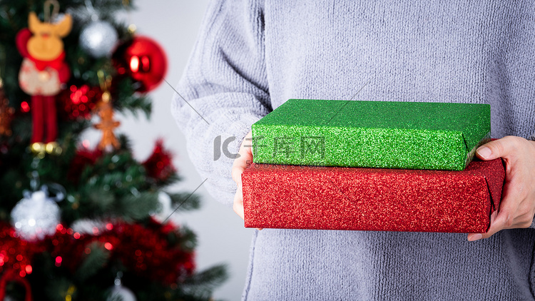 手拿着绿色和红色闪光包装纸圣诞