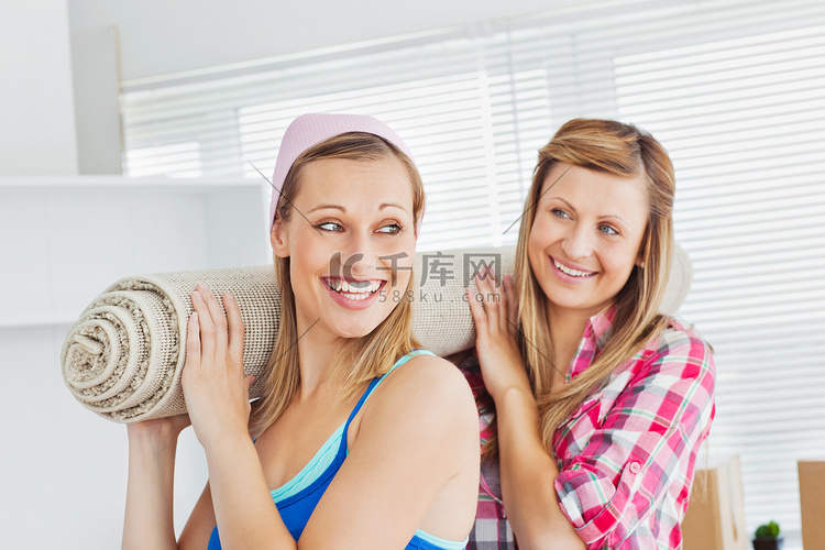 两个微笑的女人在家里拿着地毯