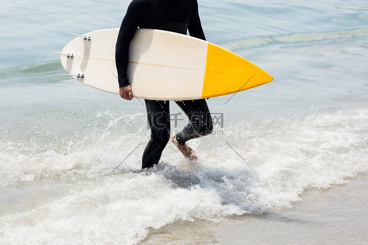 冲浪者带着冲浪板在沙滩上行走