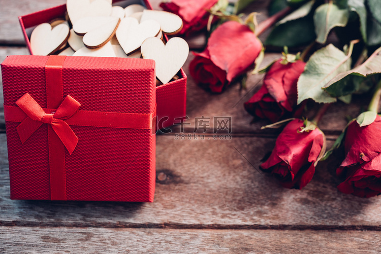木制背景上的花玫瑰和红色礼盒