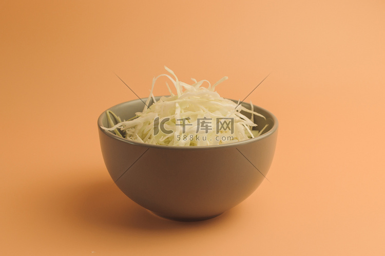 米色背景上切碎的白菜、碗里的白
