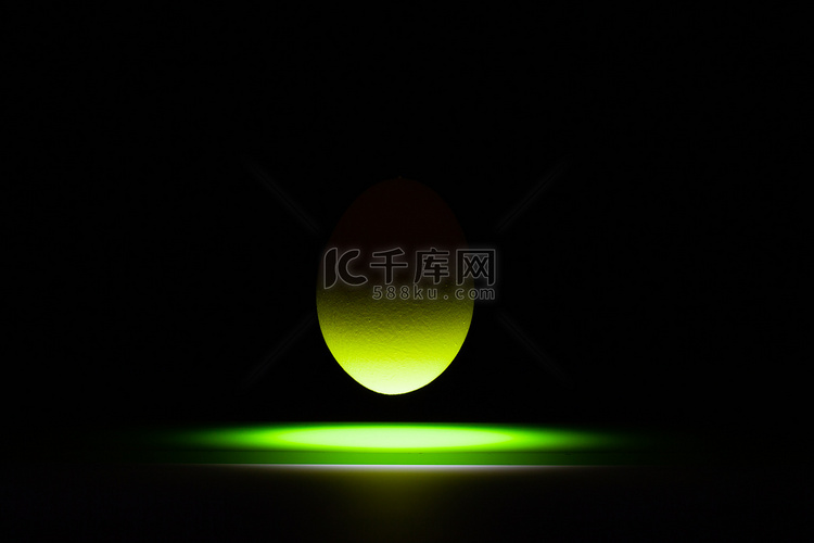 漂浮在一张黑玻璃桌上的绿色鸡蛋