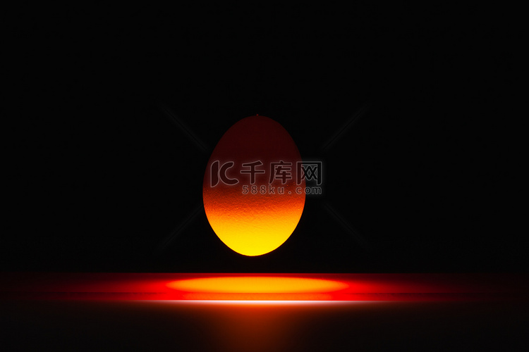 悬浮在一张黑玻璃桌上的红色鸡蛋