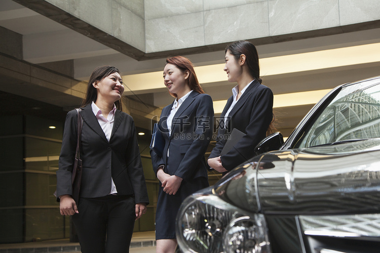 三位年轻女商人在停车场见面聊天