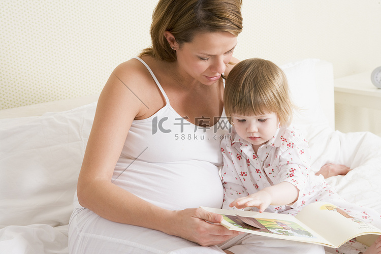 孕妇在卧室里和女儿一起看书