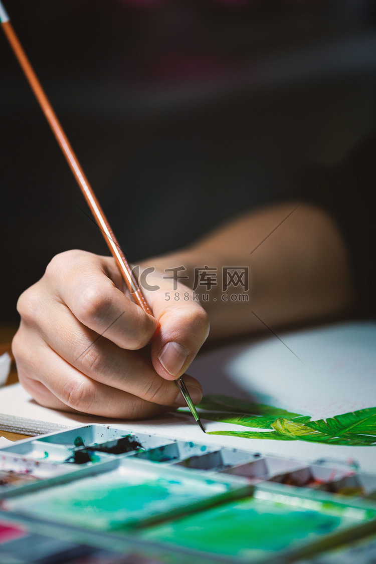 女人的手用小画笔在白纸上作画