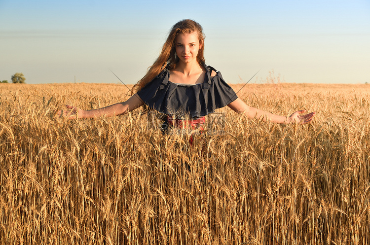 一位身穿豌豆裙的长发女子站在田