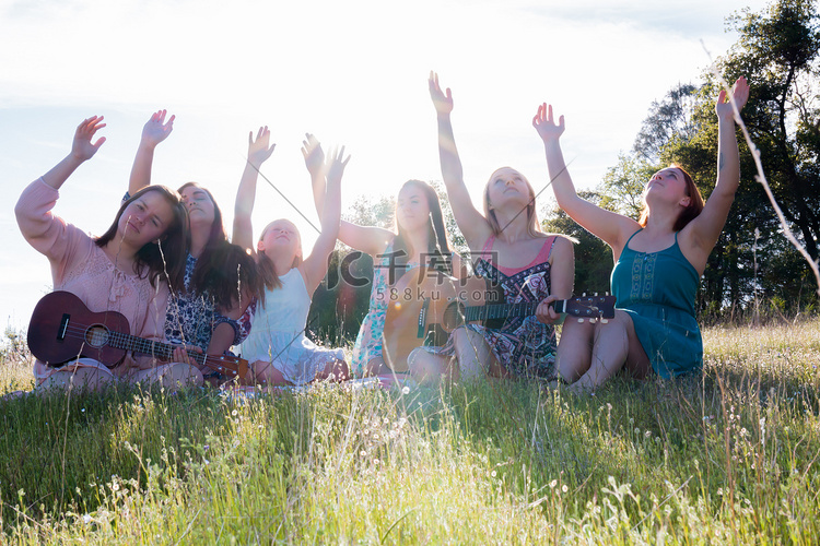 女孩们坐在一起在草地上唱歌和演