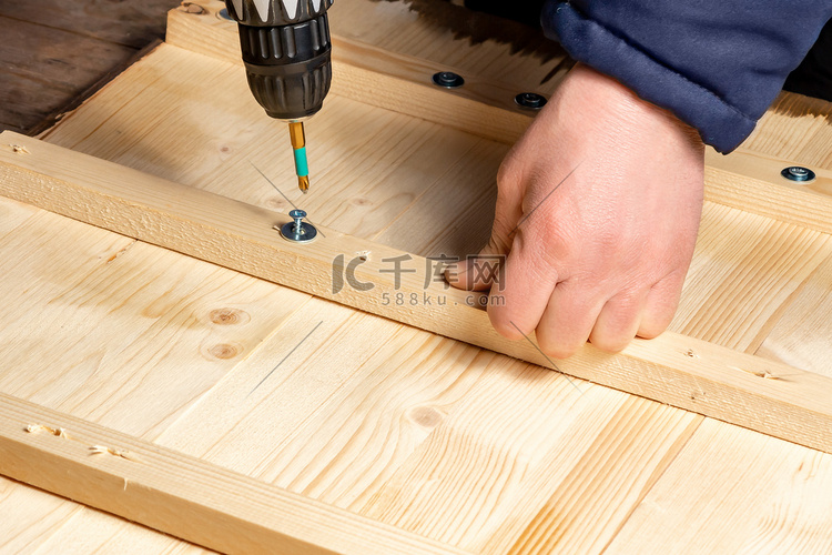 男手用螺丝刀将木块拧到木板上