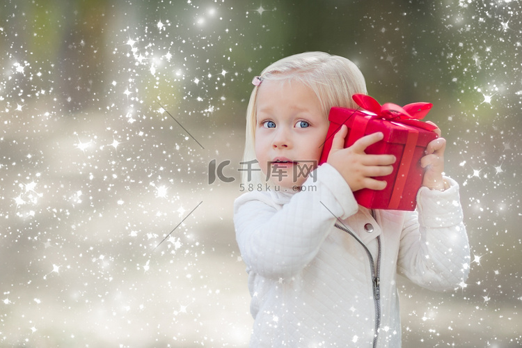 女婴拿着红色圣诞礼物在户外与雪