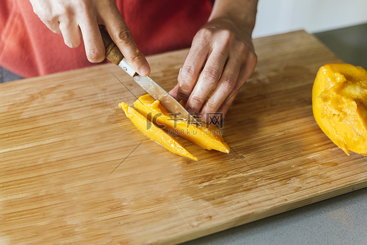 女人在木板上切芒果准备健康沙拉