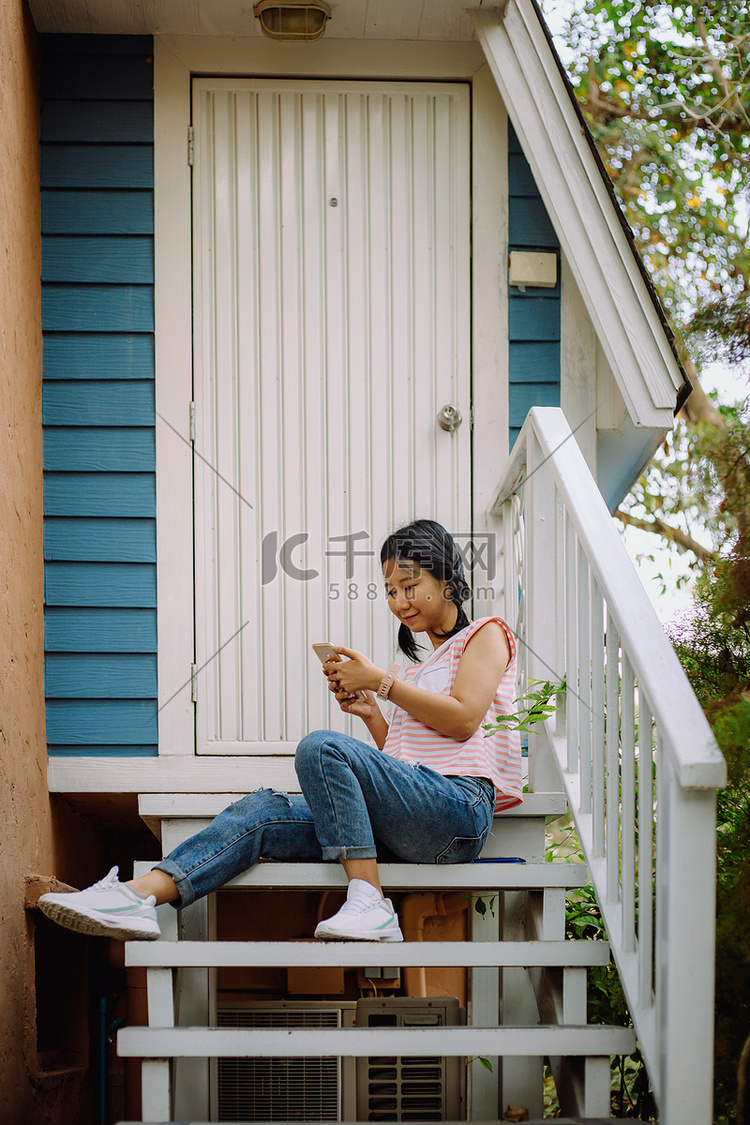 在家使用智能手机的年轻亚裔女性