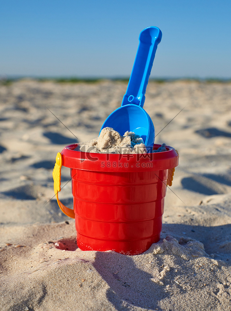 海边有沙子和铲子的婴儿红色塑料