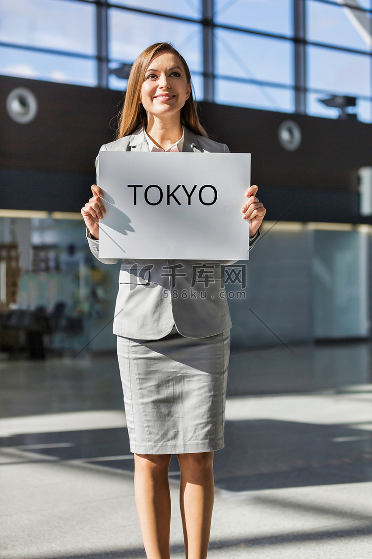 在机场到达区手持带有东京标牌的